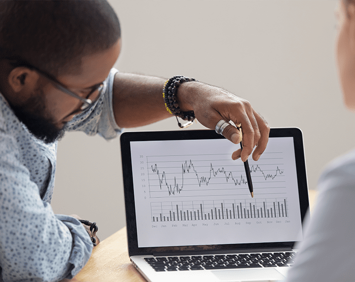 Focused african analyst showing client or colleague annual financial report analyzing business data on laptop screen using software for digital graphic statistic analysis, economic market graphs